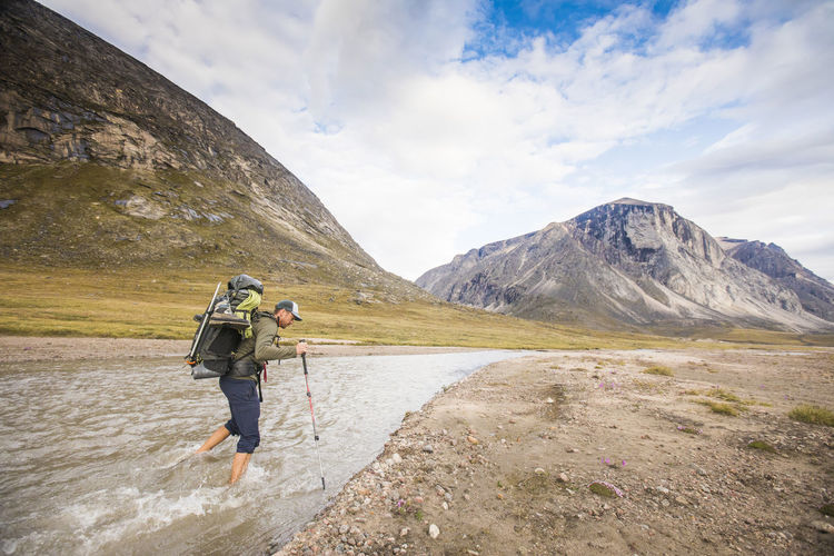 Backpacker crosses river in the arctic.