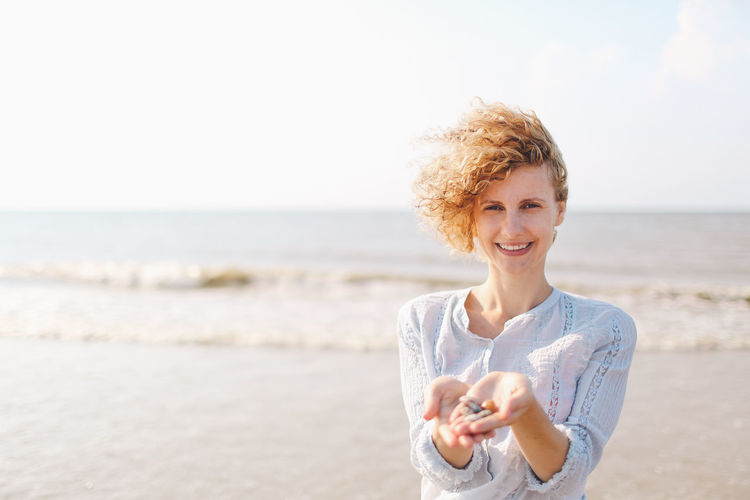 Woman holding seashells on sunny beach