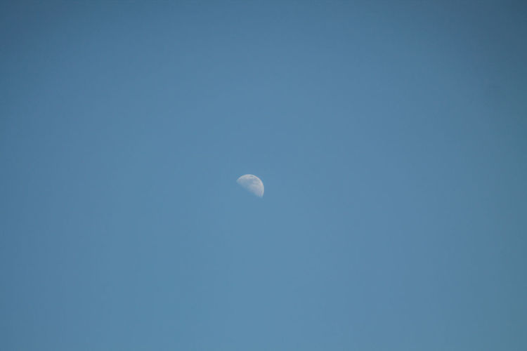 Low angle view of moon against blue sky