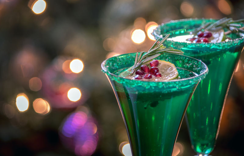 Champagne in
 holiday glasses, are garnished with lime, pomegranate seeds and a sprig of rosemary
