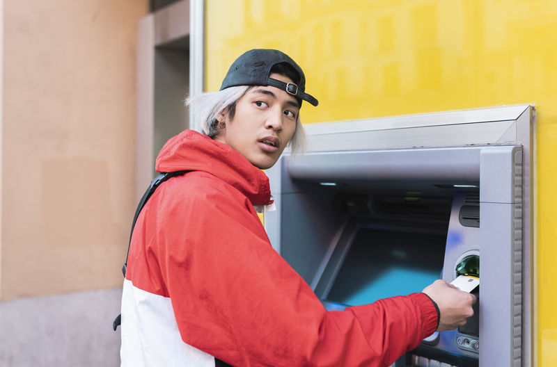 Young man withdrawing money at atm machine