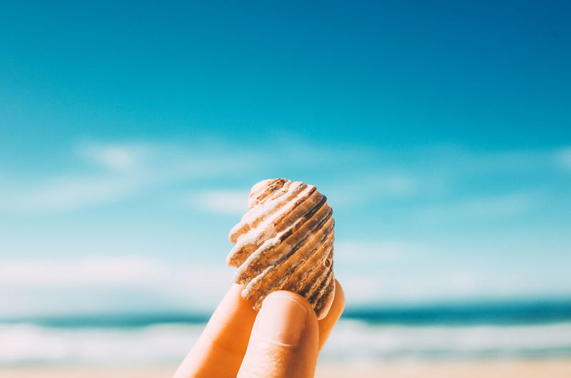 Close-up of hand holding ice cream against beach