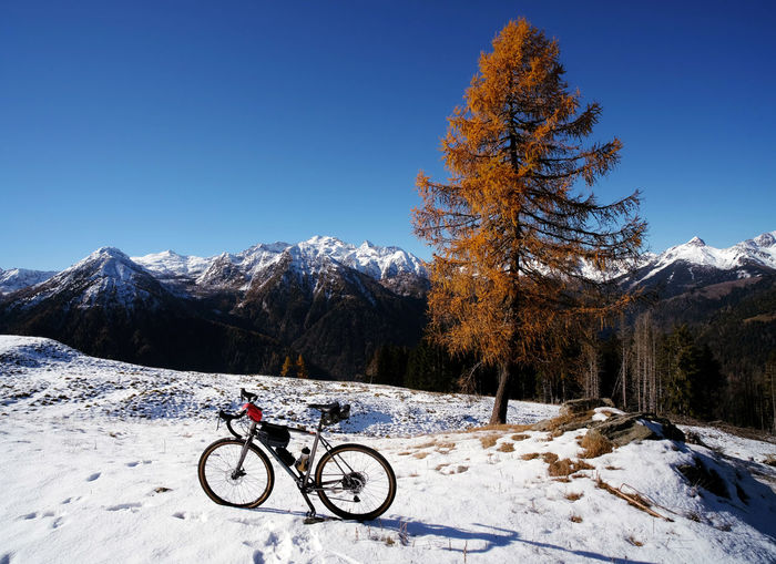 Bicycle parked on snow covered mountain against sky