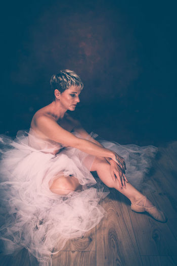 Semi-naked woman wearing tulle tutu against black background