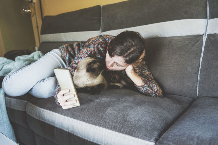 Woman taking selfie while kissing cat at home