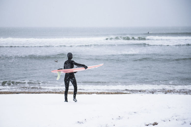Woman going surfing during winter snow