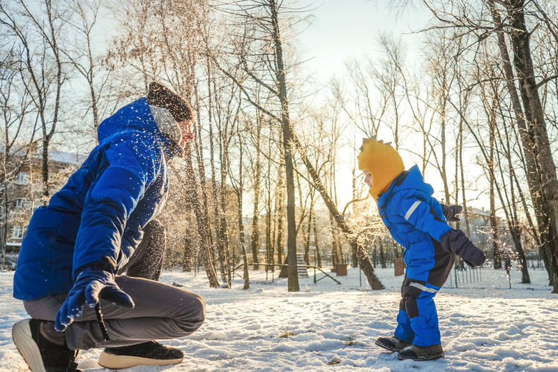 Father and son playing with snow in forest