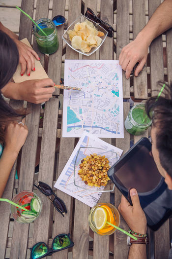 High angle view of friends discussing on map while sitting in restaurant