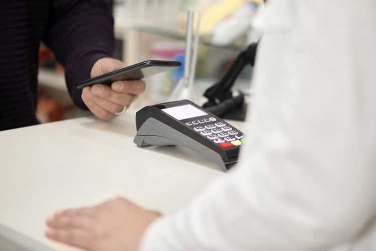 Customer making contactless payment through smart phone at checkout counter in store