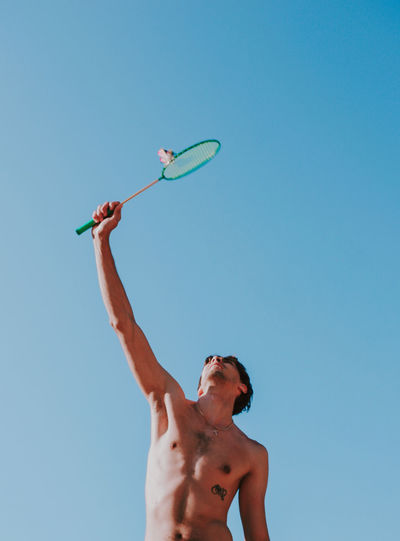 Low angle view of man playing against clear blue sky