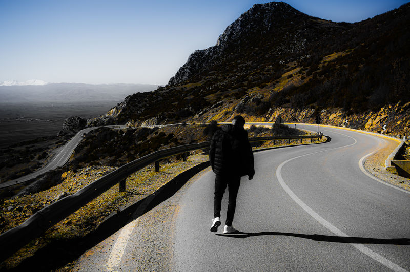 Rear view of woman on road against sky