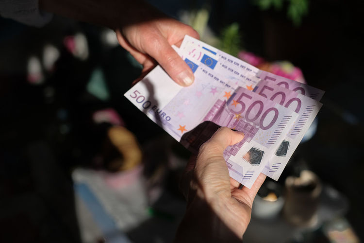 Close-up of two female hands handing over 500 euro notes 