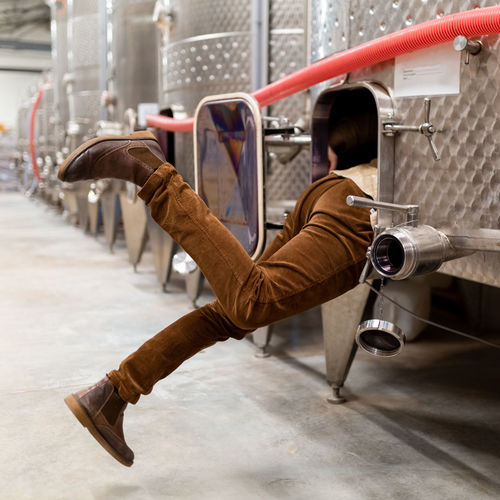 Man in brown pants stuck in wine cistern at winery warehouse production
