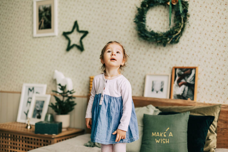 A happy girl is playing on the bed on christmas morning in a room decorated for christmas 