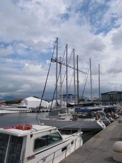 Boats in harbor against cloudy sky