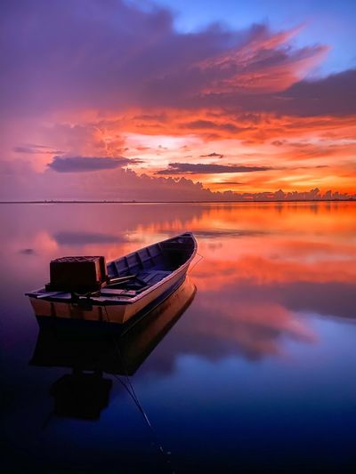 Boat moored on sea against sky during sunset