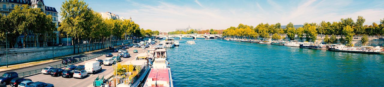 Panoramic view of vehicles by seine river against sky
