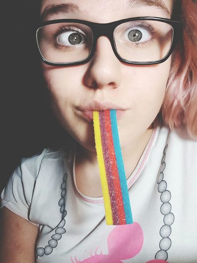 Close-up portrait of young woman eating colorful candy