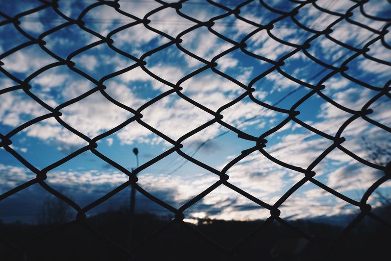 Chainlink fence on field against sky