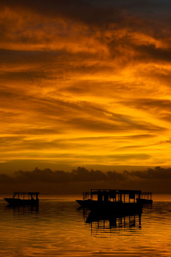 Silhouette boat in sea against orange sky