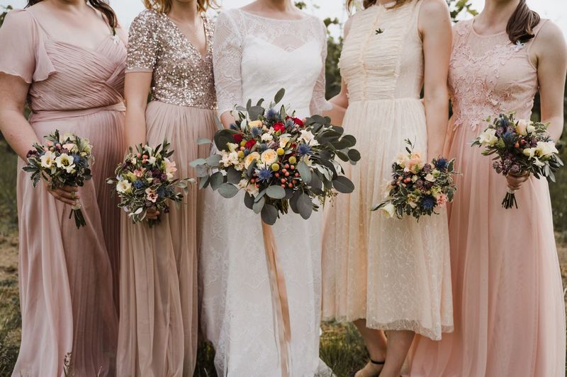 Midsection of bridegroom with bridesmaid holding bouquet