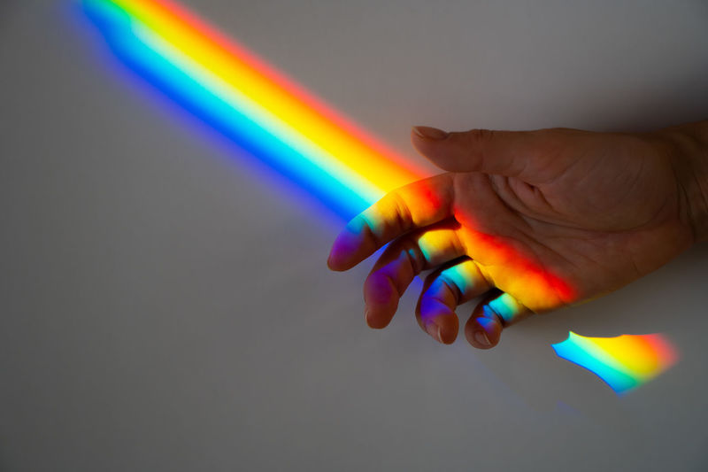 Cropped hand of person with rainbow