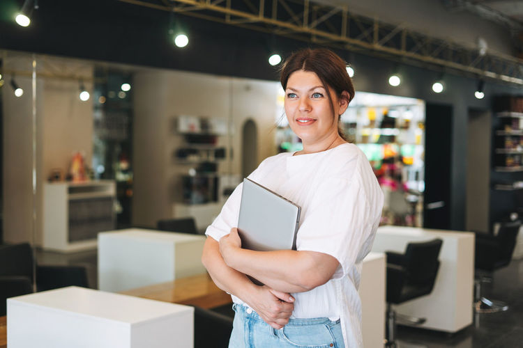 Beautiful stylish young woman plus size body positive with laptop at the beauty salon office