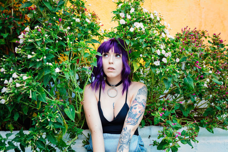 Portrait of young woman standing against plants