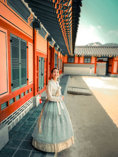 Portrait of young woman standing in front antique korean buding 