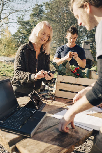 Mature woman paying male farmer through credit card at market