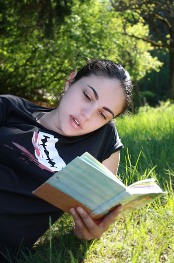 Woman reading book on field