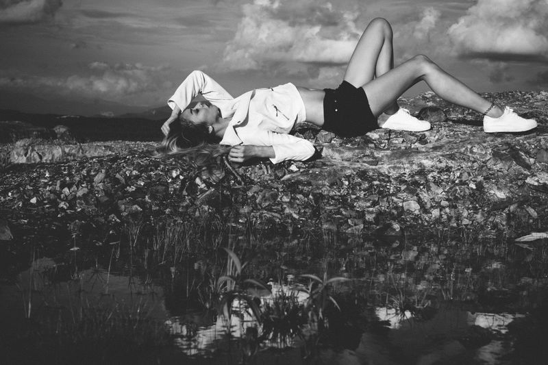 Young woman lying down at lakeshore