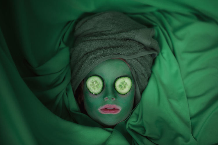 Close-up of girl face with face mask against green background