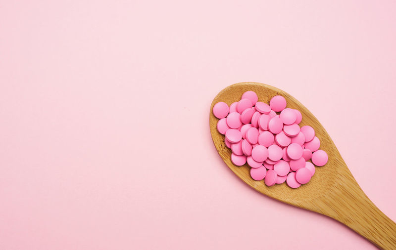 Close-up of pills in bowl against pink background