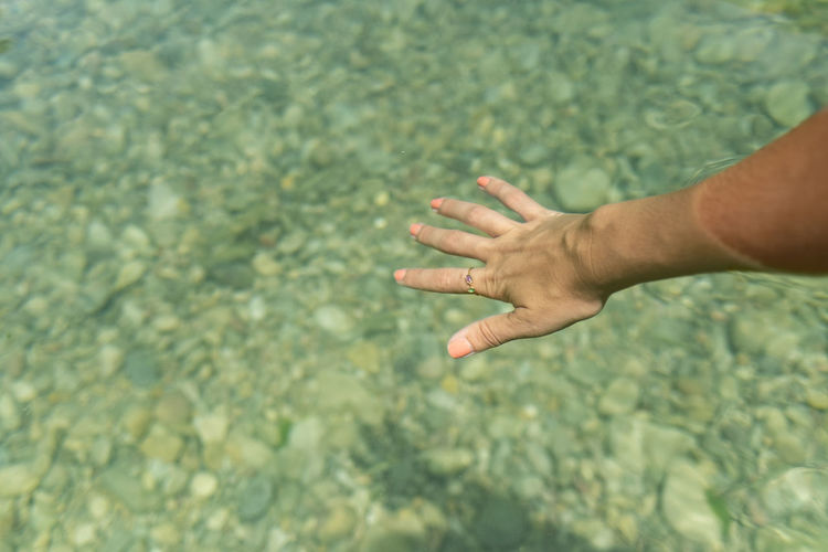 A female hand moving in the turquoise water of a natural pool. fingers are clear through the water.
