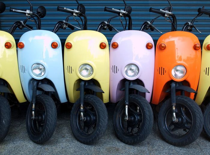 Colorful motor scooters parked in row on footpath