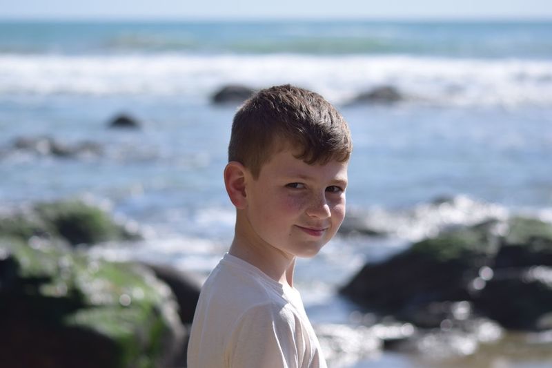 Portrait of smiling boy against sea at beach