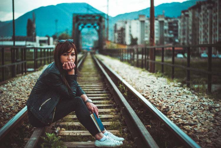 Girl sitting on railroad track