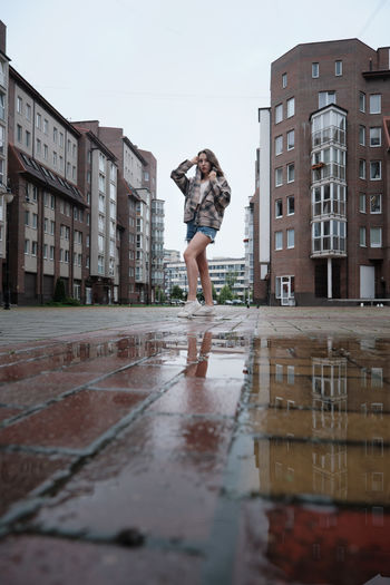 Girl near autumn puddle with reflections on city square