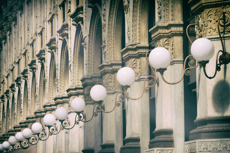 Repetetive classical columns and arches with lamps in milano, italy