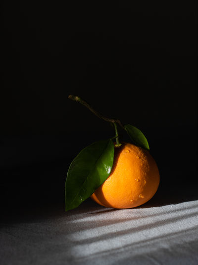 Close-up of orange fruit on table against black background