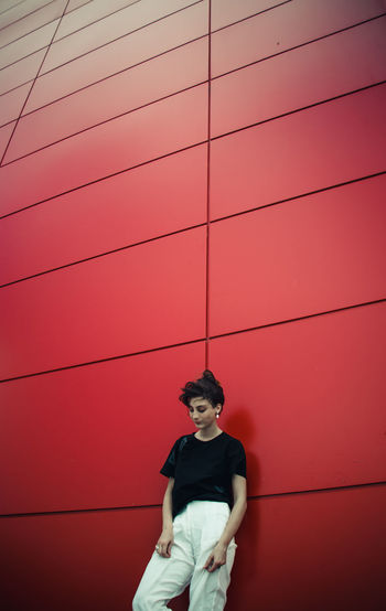 Young woman standing against red wall