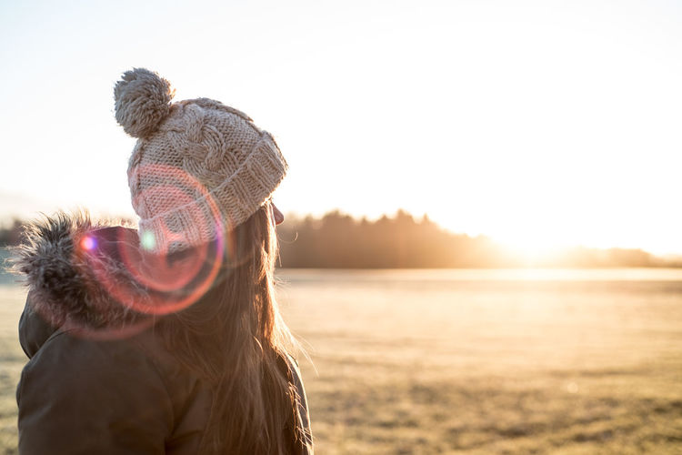 Woman wearing hat against sun during sunset