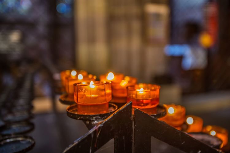 Lit tea light candles in temple against building