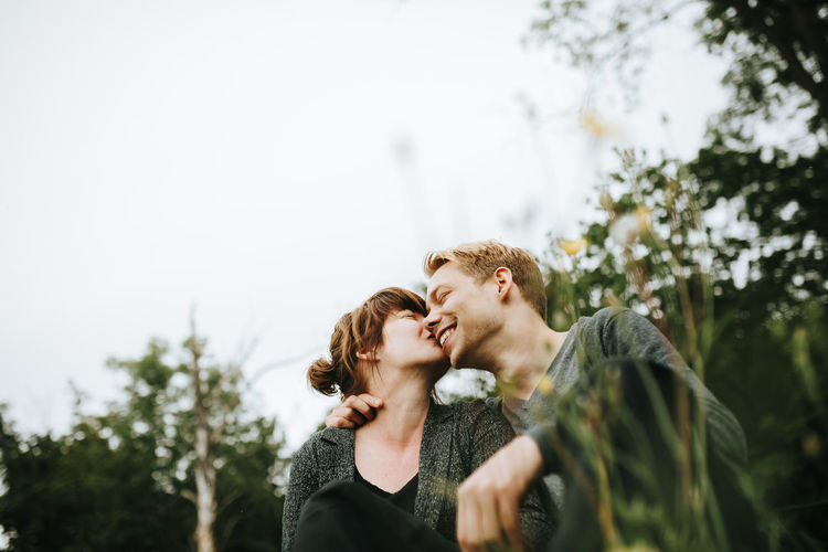 Young couple kissing against plants