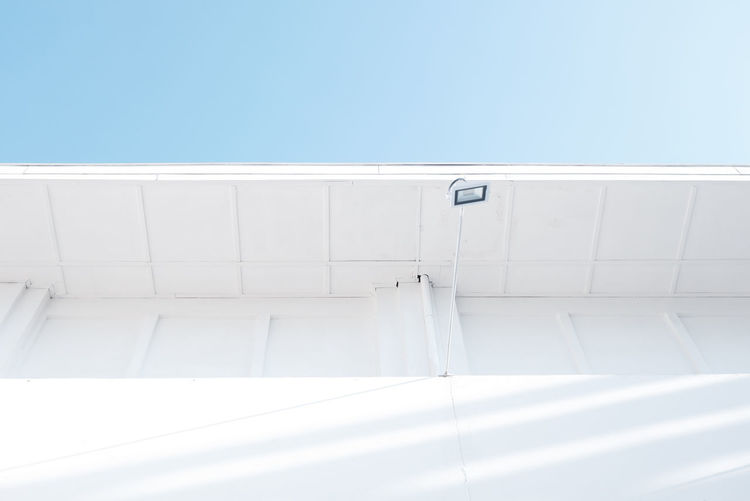 Low angle view of white wall against clear blue sky