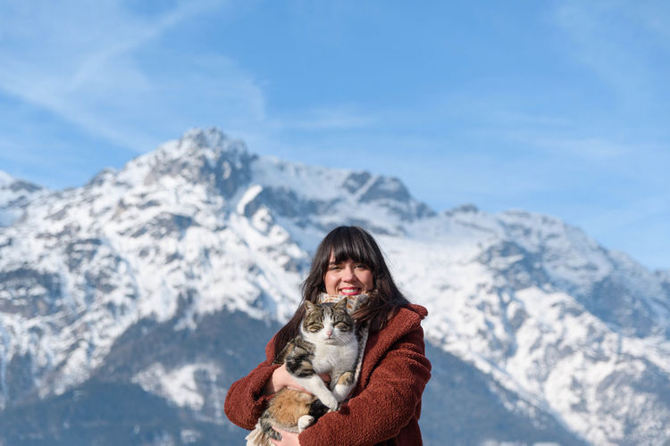 Portrait of a young woman holding a cat. mountains, winter, depth of field.
