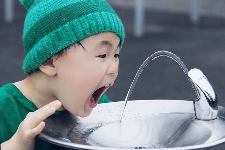 Little boy trying to reach drinking fountain