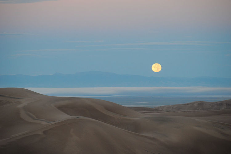 Moon setting over sand dunes