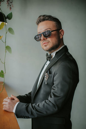 Young man wearing sunglasses standing against wall